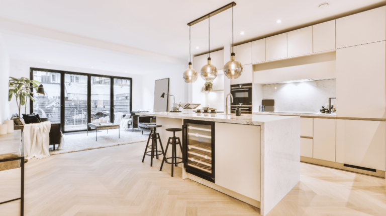 Vue d’une cuisine lumineuse et ouverte avec mobilier moderne, îlot central en marbre et éclairages suspendus